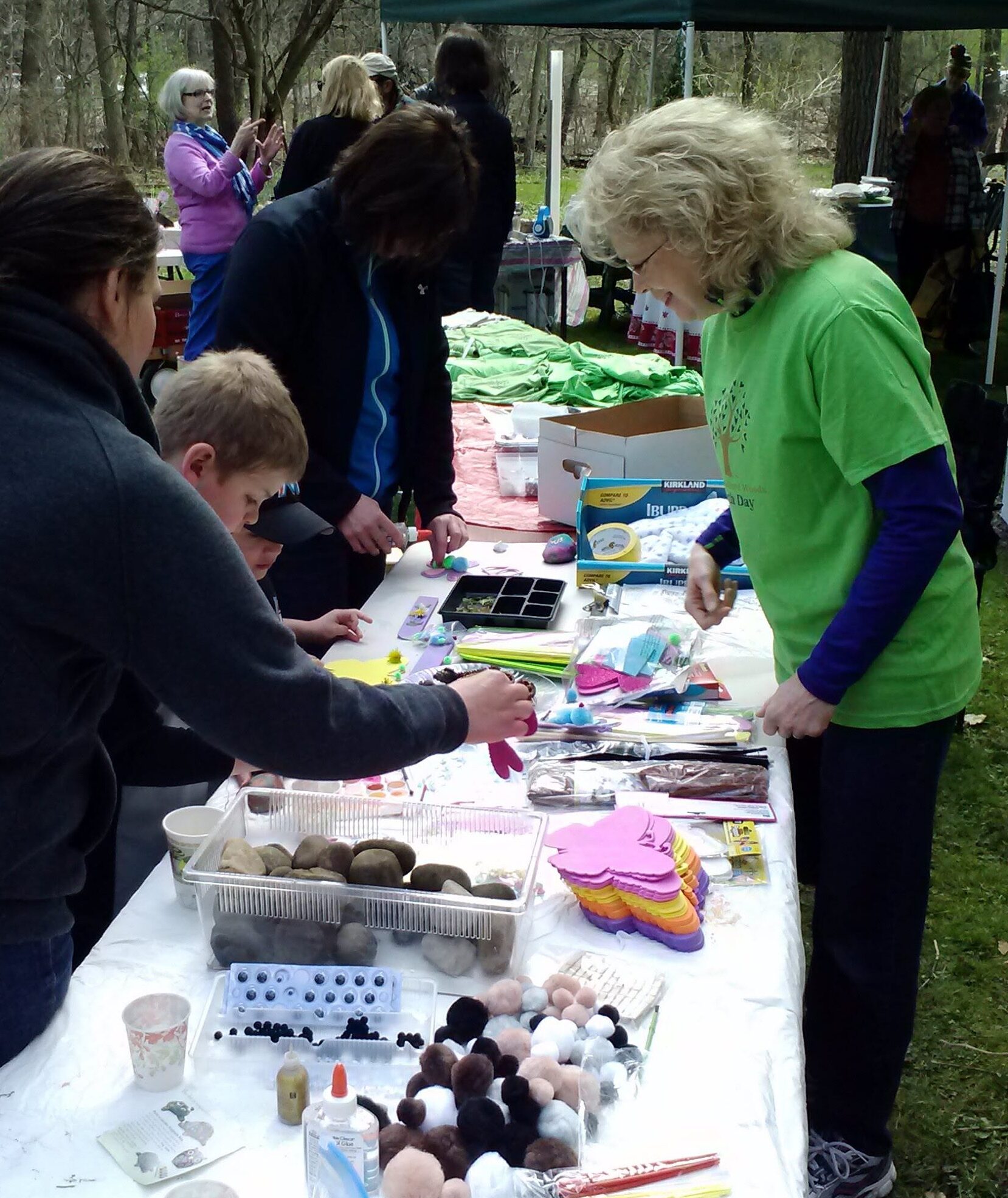 People gathered around a table with crafts and items outdoors.