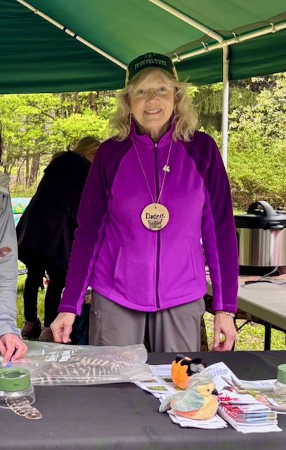 People gathered around a table with crafts and items outdoors.