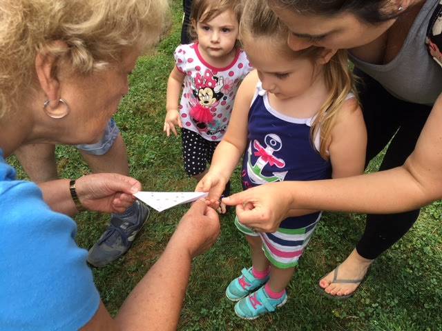 Children engaging in a hands-on outdoor learning activity with an adult.