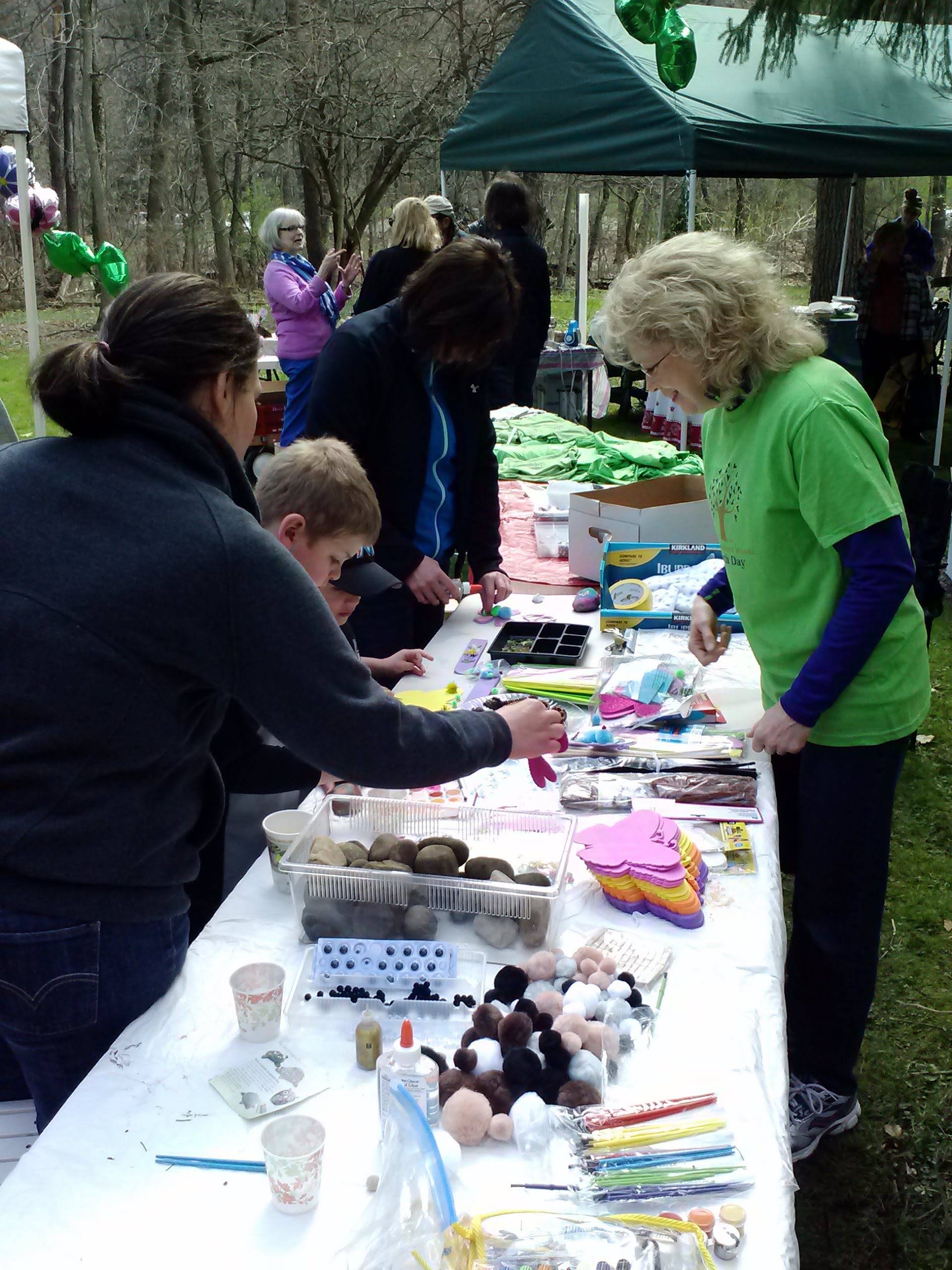 People gathered around a table with crafts and items outdoors.