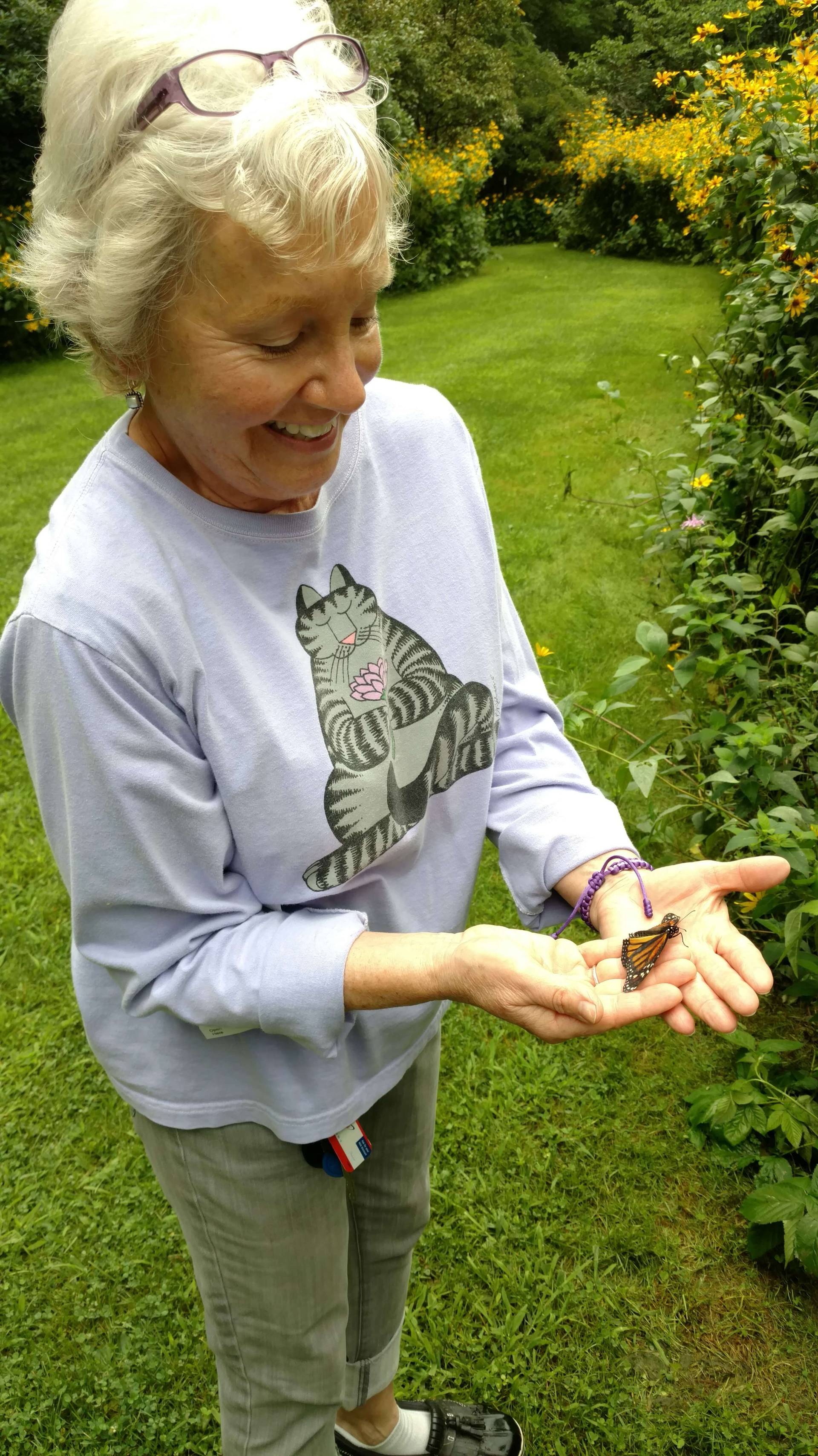 Woman holding a small bird gently in her hands outdoors.