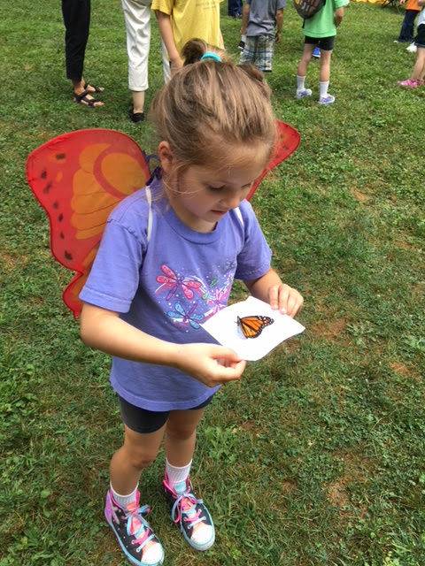 Young girl observing a butterfly on a paper.