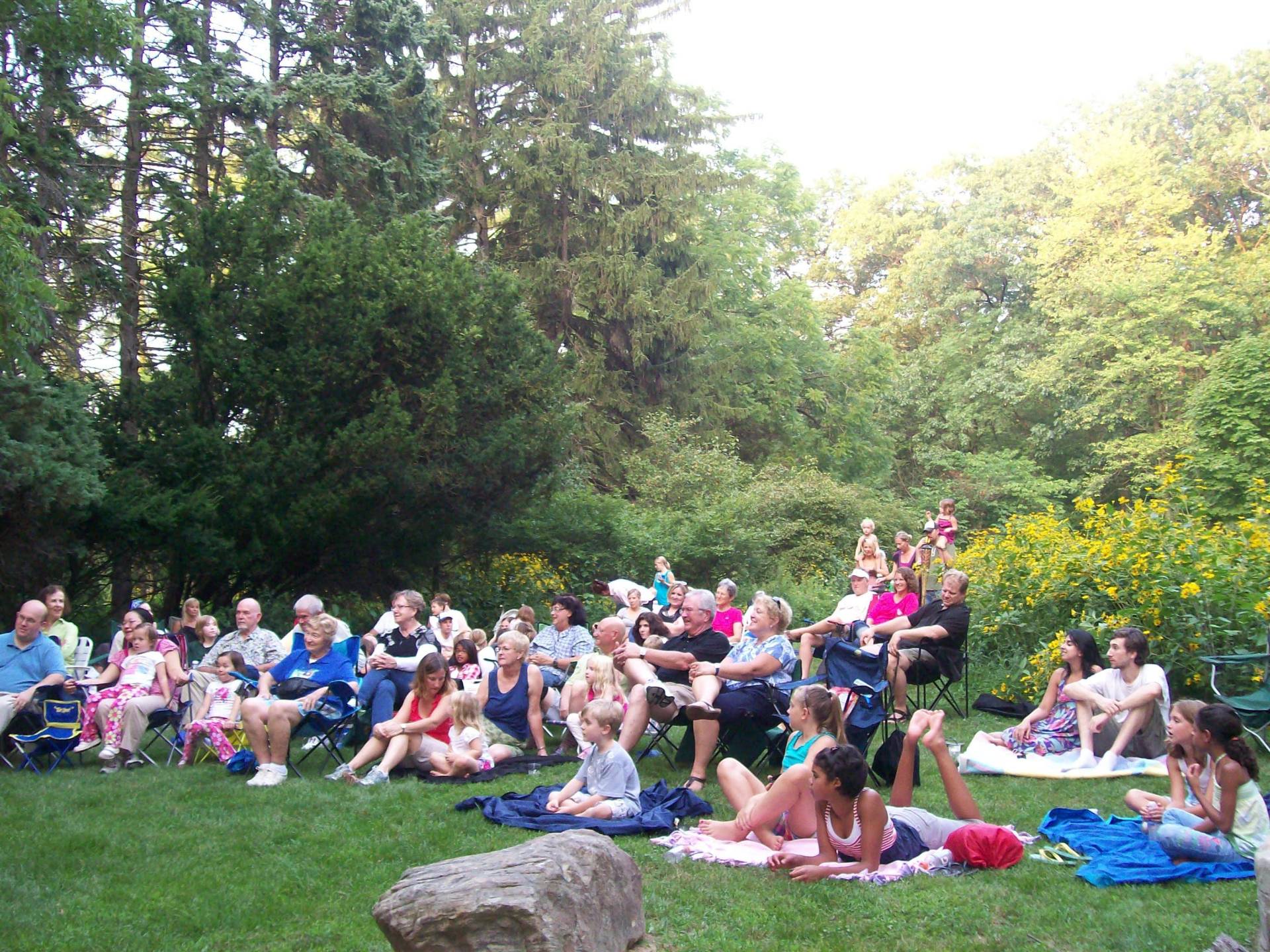 People gathered outdoors on a grassy area enjoying a sunny day.